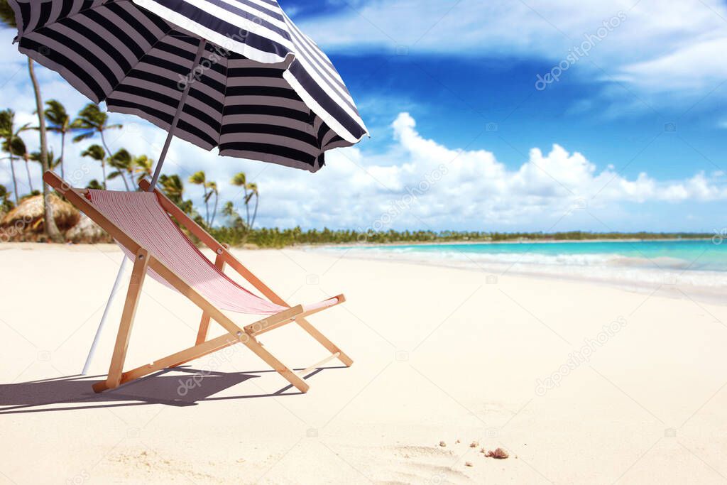 Wooden deck chairs on sandy beach near sea. Holiday background.