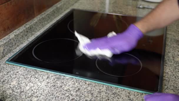 Ręce Mężczyzny Niebieskich Rękawiczkach Czyszczą Szklano Ceramiczną Płytę Kuchni Dbałością — Wideo stockowe