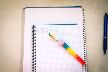 İlkokul matematik operasyonları yapan bir kız için bir çek defteri ve tek boynuzlu at kalemi. Matematik, mantık, eğitim