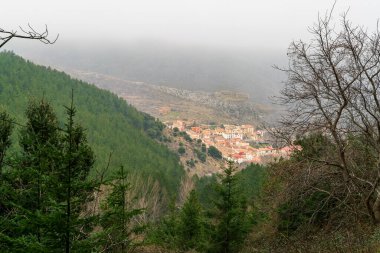  Arkadaki güzel Talamantes köyü dağın tepesinde 12. yüzyıldan kalma şatosuyla Moncayo 'nun yüksek çam ağaçları arasında yukarıdan gelen bulutlarla. Talamantes, Zaragoza, İspanya