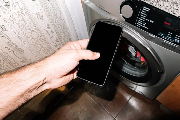 Άνθρωπος Που Ελέγχει Ένα Έξυπνο Πλυντήριο Ρούχων Smartphone Του — Φωτογραφία Αρχείου