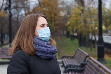 Parkta tek kullanımlık koruyucu maskeli genç Avrupalı kadın