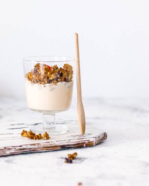 Granola breakfast with fruits, nuts, yogurt in the glass, on a gray stone background, healthy sugar free breakfast, morning meal.