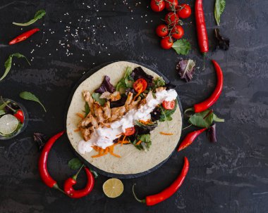 Bir yaprak ekmek üzerine lavaş taze sebzeler ve tavuk eti koyu arkaplanda hafif sos.