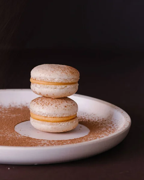 macarons isolat , macarons on a plate . on dark background upside backside  flowers and woman's hands 