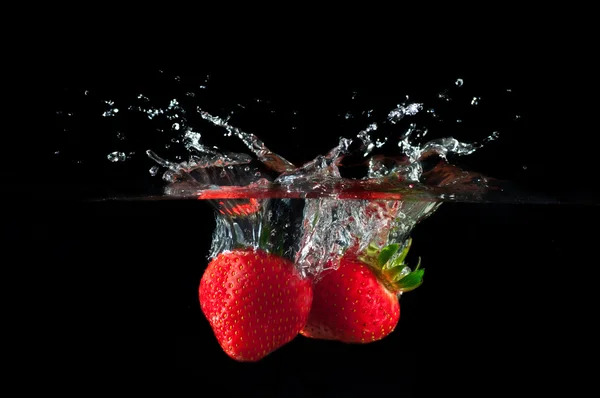 Erdbeeren, die ins Wasser spritzen lizenzfreie Stockbilder