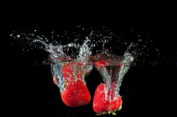 Erdbeeren, die ins Wasser spritzen Stockbild