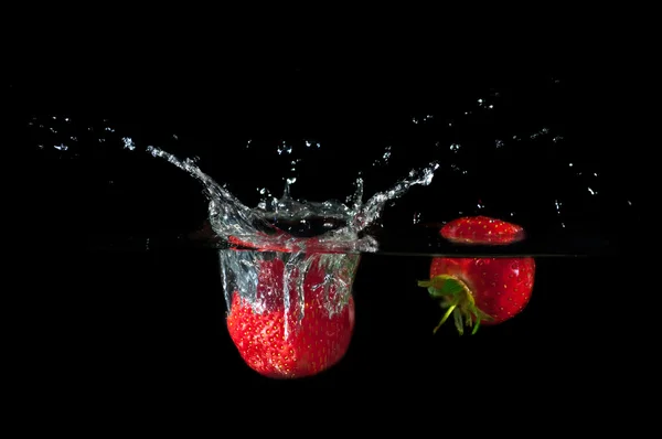 Strawberries splashing into water — Stock Photo, Image