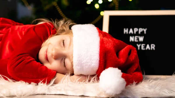 Una Niña Disfraz Navidad Santa Claus Sombrero Está Durmiendo Bajo — Foto de Stock
