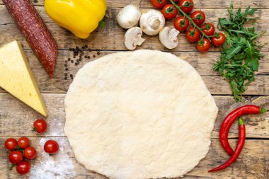 Pişirmeden önce pizza ve çiğ pizza yapmak için malzemeler, ahşap bir masada, üst tarafta. Yüksek kalite fotoğraf