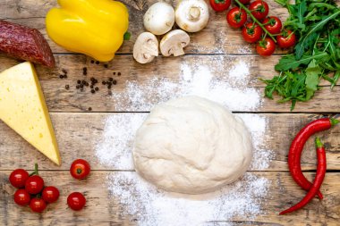 Pizza yapmak için malzemeler, pişirmeden önce, ahşap bir masa üzerinde, üst görünüm, adım adım tarif