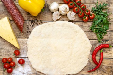 Pişirmeden önce pizza ve çiğ pizza yapmak için malzemeler, ahşap bir masada, üst tarafta. Yüksek kalite fotoğraf