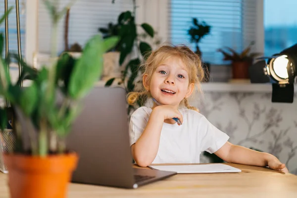 Ευτυχισμένο μικρό κορίτσι vlogger κάθεται στο φορητό υπολογιστή κοιτάζοντας κάμερα, χαμογελώντας και κάνοντας online βίντεο κλήση βίντεο βίντεο blog εγγραφή, πορτρέτο — Φωτογραφία Αρχείου