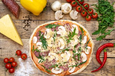 Pişirmeden önce pizza ve çiğ pizza yapmak için malzemeler, ahşap bir masada, üst tarafta. Yüksek kalite fotoğraf