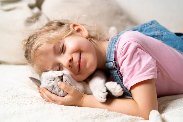 Pequena Menina Loira Feliz Jaz Cama Abraça Gatinho Dormindo Branco — Fotografia de Stock