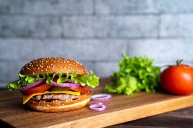 Tahtada hamburgerli, domatesli, peynirli ve marullu..