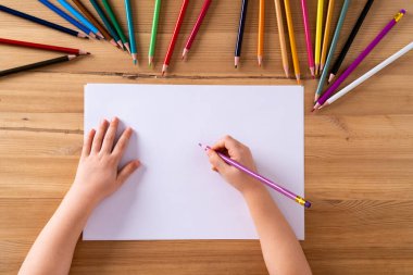 Çocukların elleri masanın üstünde ve beyaz bir sayfa kağıt ve renkli kalemler, çocukların yaratıcılığı kavramı.