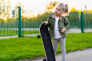 Şehirde kaykaylı küçük sarışın kız.