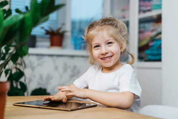 Ένα Μικρό Κορίτσι Κάθεται Ένα Τραπέζι Ένα Δισκίο Χέρια Της — Φωτογραφία Αρχείου