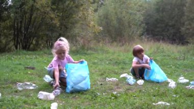 Çocuklar plastik çöpleri çıkarıp açık havada çözünebilir bir çöp torbasına koyuyorlar. Ekoloji, atık işleme ve doğa koruma kavramı. Çevre koruma