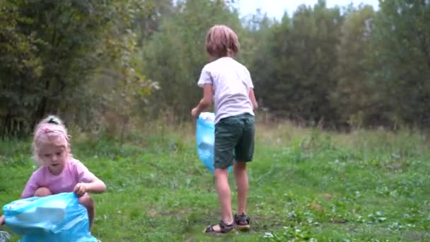 A gyerekek kiveszik a műanyag szemetet, és egy biológiailag lebomló szemeteszsákba teszik a szabadban. Az ökológia, a hulladékfeldolgozás és a természetvédelem fogalma. Környezetvédelem — Stock videók