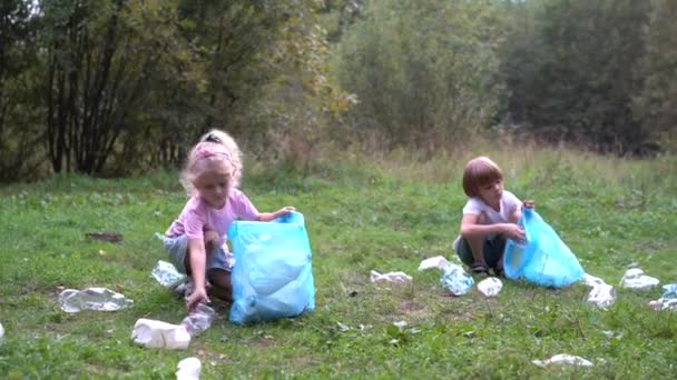 子供たちはプラスチックごみを取り出し、生分解性のゴミ袋に入れます。生態学、廃棄物処理と自然保護の概念。環境保護 — ストック動画