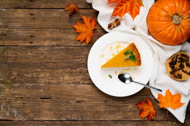 Balkabağı turtası, sağdaki tahta masada, balkabağı ve sonbahar yaprakları, soldaki boşluğu kopyalayın..