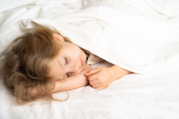 A little blonde is sleeping sweetly in a bed with white underwear. space for the text. healthy sleep of the child.