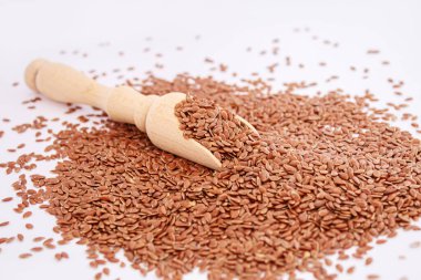 Tahta bir kaşıkta keten tohumlarının beyaz arka planda yakın plan keten tohumları. Odaklanma.