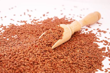 Tahta bir kaşıkta keten tohumlarının beyaz arka planda yakın plan keten tohumları. Odaklanma.