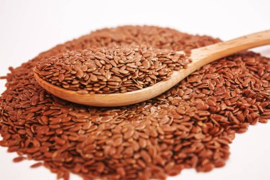 Tahta bir kaşıkta keten tohumlarının beyaz arka planda yakın plan keten tohumları. Odaklanma.