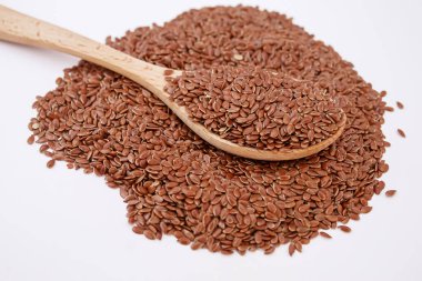 Tahta bir kaşıkta keten tohumlarının beyaz arka planda yakın plan keten tohumları. Odaklanma.