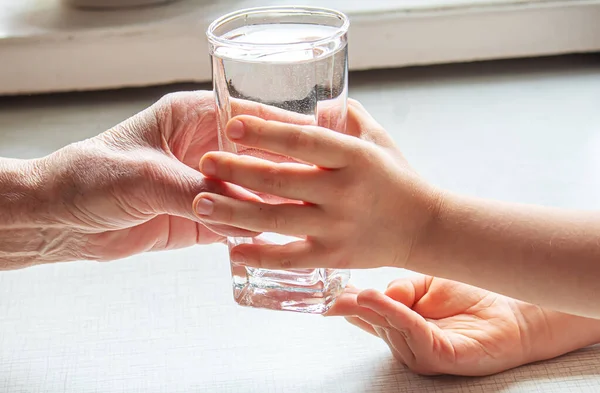 Grandmother giving a glass of clean water to a child. Selective focus. nature.