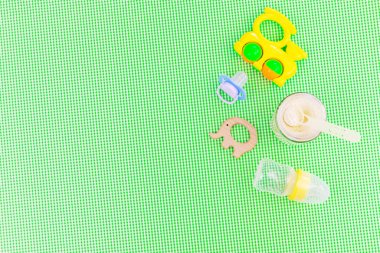 Yeşil arka planda bebek aksesuarları ve yemek. Seçici odaklanma bebeğim.