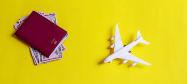 Seyahat hazırlama konsepti uçak, para, pasaport, sarı arka plan. Seçici odaklanma. Tatiller