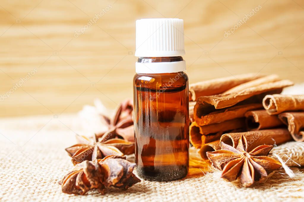 Essential oil bottle with cinnamon stick, star anise on wooden background. Selective focus.nature