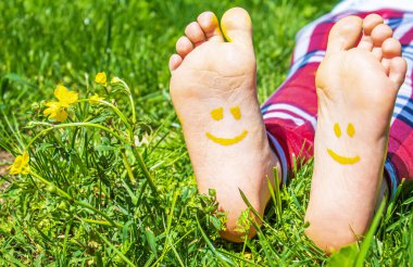 Yeşil çimlerin üzerinde gülümseyen boya desenli çocuk ayakları. Seçici odaklanma. Doğa.