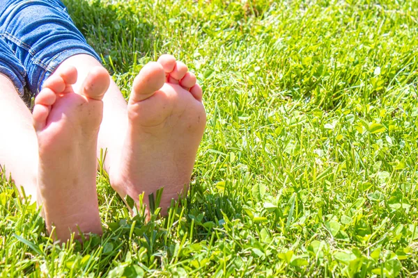 Çocuk yeşil çimlerin üzerinde yatıyor. Çocuk bahar parkında eğleniyor. Seçici odaklanma. insanlar