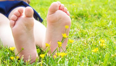 Çocuk yeşil çimlerin üzerinde yatıyor. Çocuk bahar parkında eğleniyor. Seçici odaklanma. insanlar