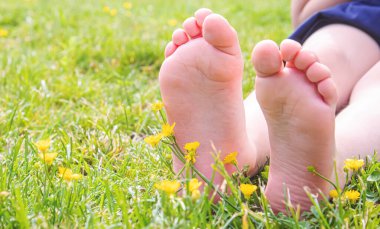 Çocuk yeşil çimlerin üzerinde yatıyor. Çocuk bahar parkında eğleniyor. Seçici odaklanma. insanlar