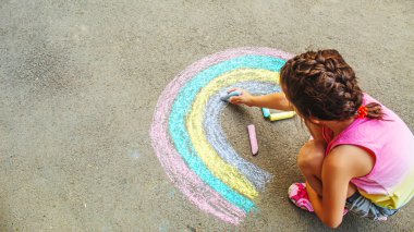 Bir çocuk asfalta bir gökkuşağı çizer. Seçici odaklanma. çocuk.