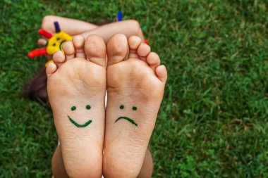 Baby feet with paint pattern are smiling and sad on the green grass. Selective focus. nature.