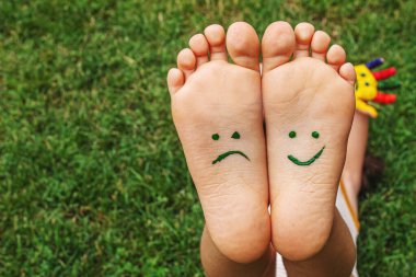 Baby feet with paint pattern are smiling and sad on the green grass. Selective focus. nature.