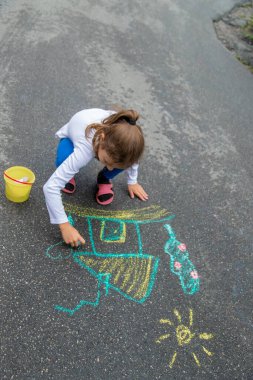 Çocuk asfalta tebeşirle çizer. Seçici odaklanma. Doğa.