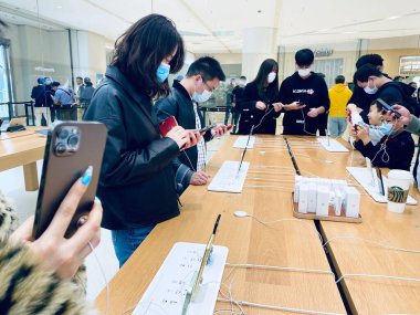 Suzhou, Jiangsu Eyaleti, Çin - 25 Ekim: Yepyeni 5G IPhone 12 'yi tutan şık bir el. Daha çok Apple Store Suzhou Şubesindeki Çinli müşteriler covid-19 'u önlemek için maske takıyor..