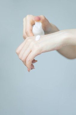 Soğuk mevsim işçilerinin cilt korumasına ihtiyacı var. Gri arkaplana fotokopi alanı ile koruyucu krem süren bir kadının yakın çekimi.. 