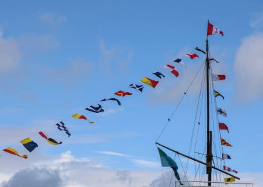 Mavi gökyüzüne işaret bayraklı direkler.