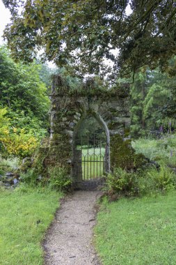 Bahçedeki eski taş giriş kapısı. Metal kapıları olan bir çit. İrlanda