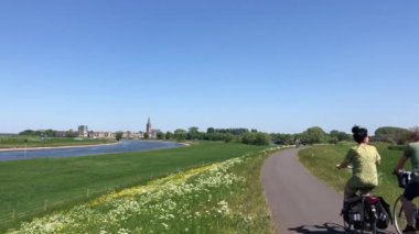 Gelderland, Hollanda 'daki Doesburg' a doğru IJssel nehri boyunca bisiklet süren bir çift.