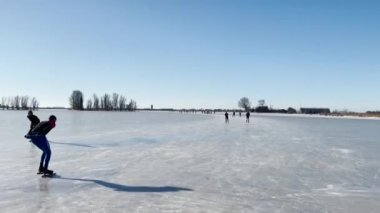 Friesland, Hollanda 'daki Sneek yakınlarında donmuş bir gölde buz pateni yapan insanlar.